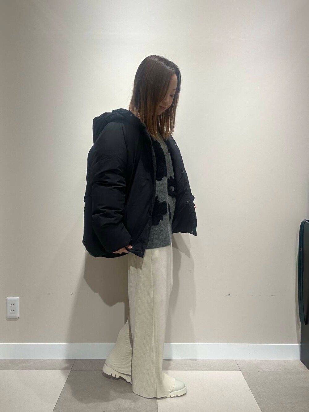 ホワイト系のその他パンツ、ブラック系のダウンジャケット/コート、グレー系のニット/セーターを着用したレディースの冬コーディネートの2枚目の写真