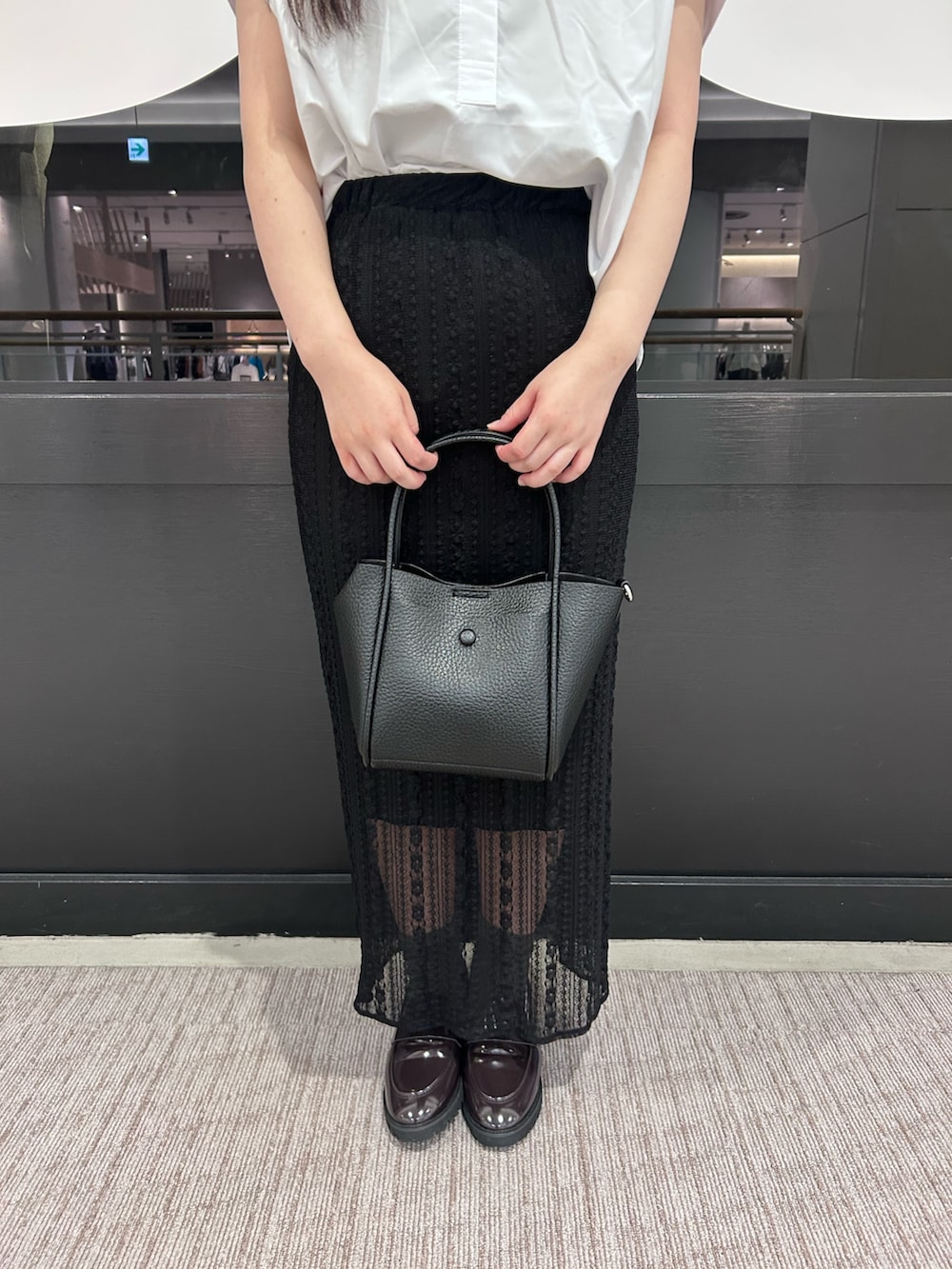 ブラック系のトートバッグ、ブラック系のスカート、ホワイト系のシャツ/ブラウスを着用したレディースの夏コーディネートの5枚目の写真