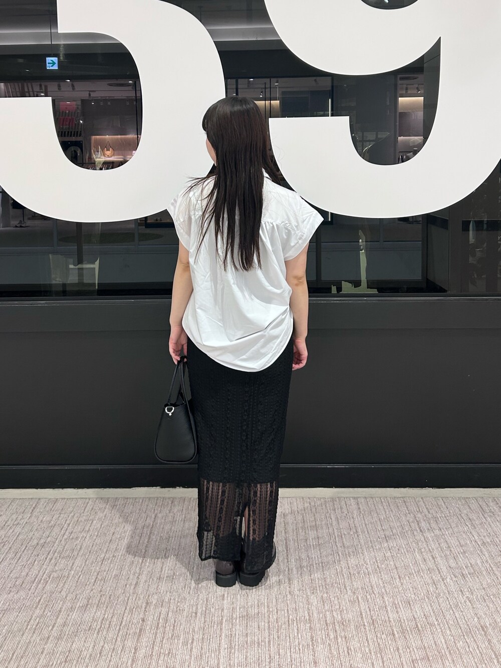 ブラック系のトートバッグ、ブラック系のスカート、ホワイト系のシャツ/ブラウスを着用したレディースの夏コーディネートの3枚目の写真