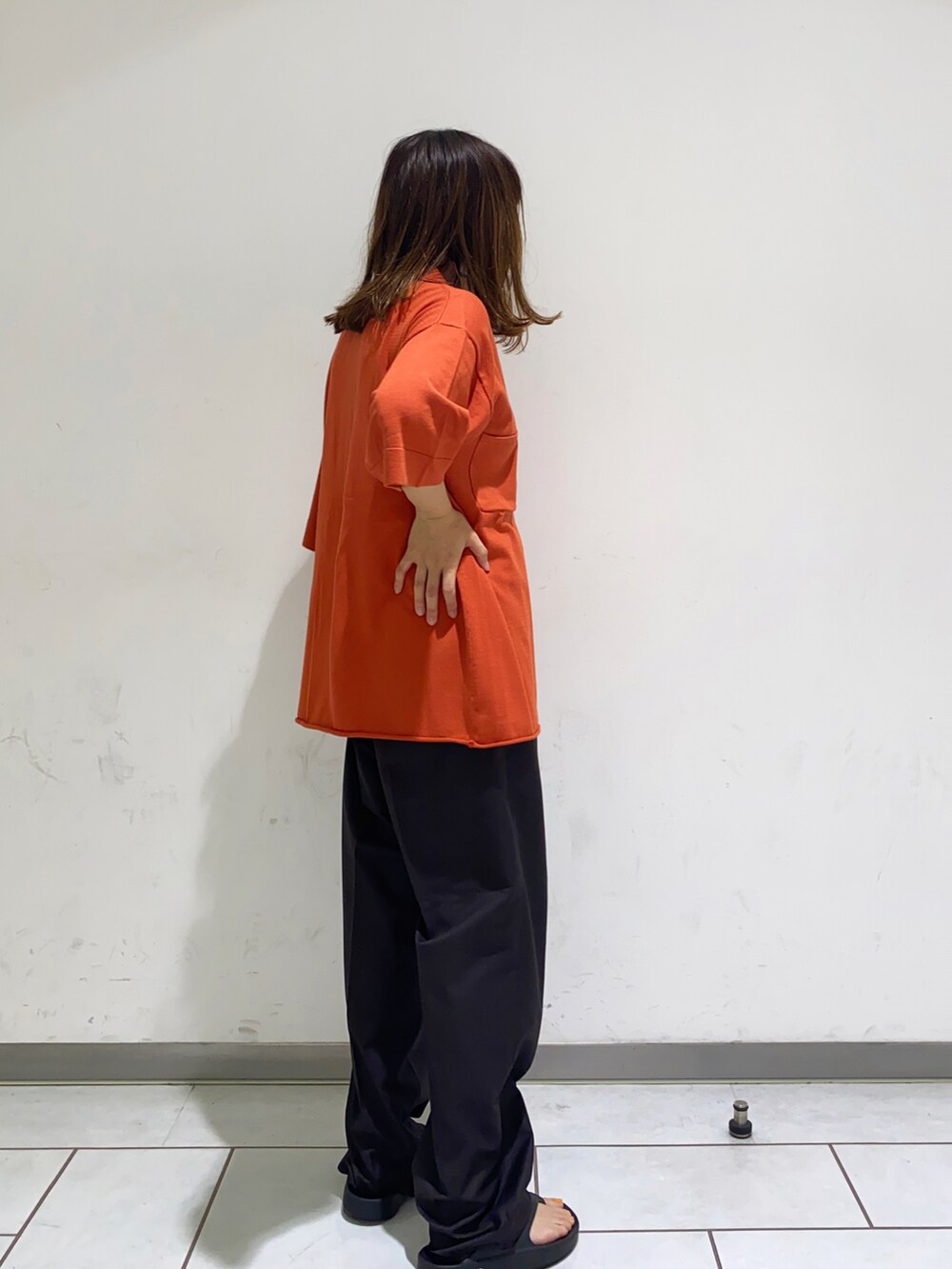 オレンジ系のニット/セーター、ブラウン系のその他パンツを着用したレディースの夏コーディネートの2枚目の写真