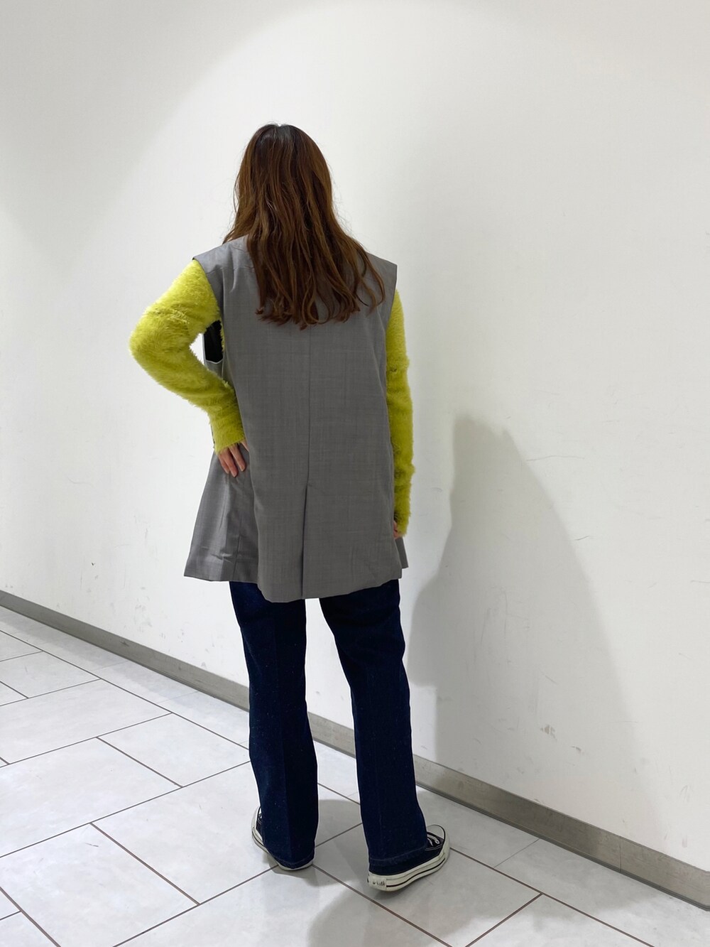 イエロー系のニット/セーター、グレー系のベスト、ブルー系のデニムパンツを着用したレディースの春コーディネートの3枚目の写真