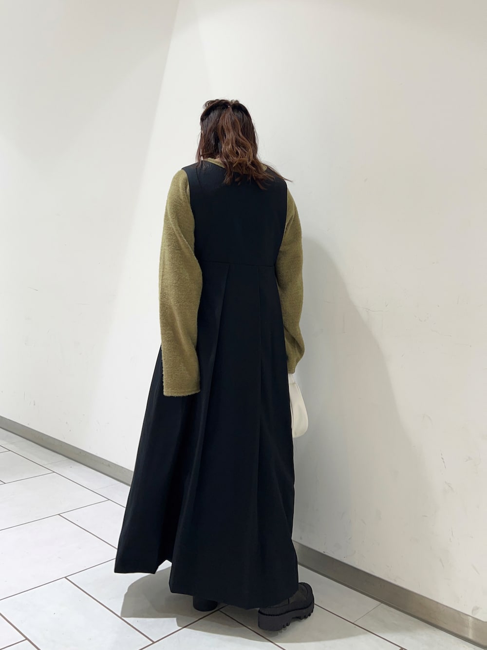 ブラック系のワンピース、グリーン系のTシャツ/カットソー、ブラック系のブーツを着用したレディースの冬コーディネートの2枚目の写真