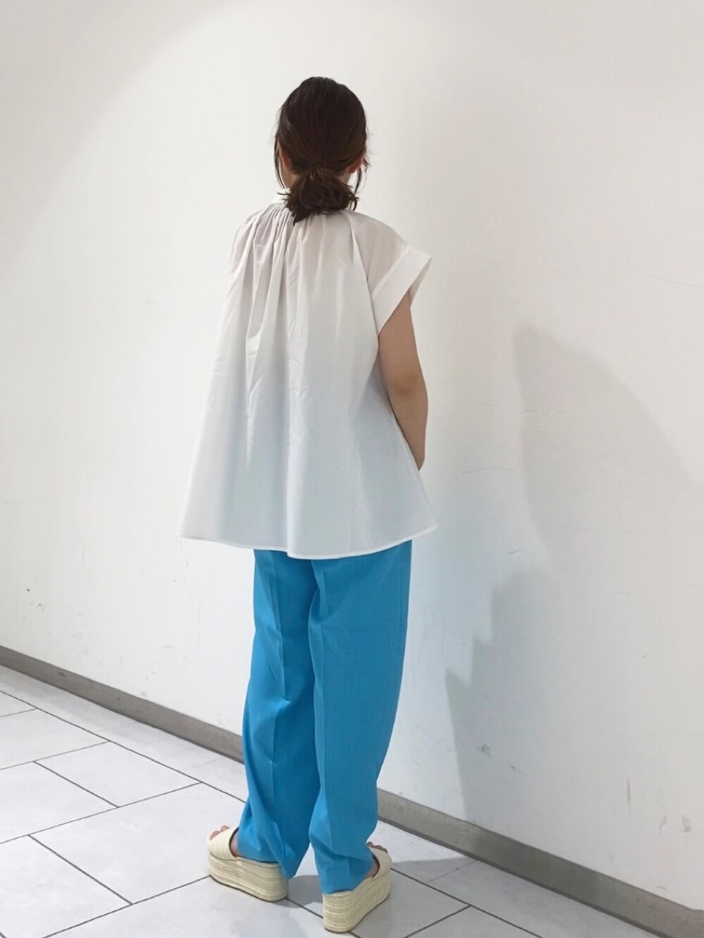 ホワイト系のシャツ/ブラウス、ブルー系のスラックス、ホワイト系のサンダルを着用したレディースの夏コーディネートの2枚目の写真