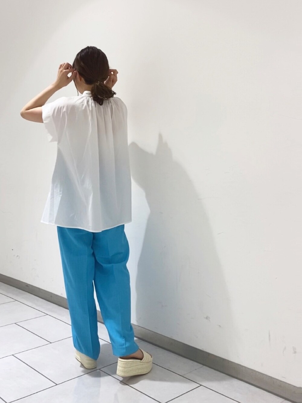 ホワイト系のシャツ/ブラウス、ブルー系のスラックス、ホワイト系のサンダルを着用したレディースの夏コーディネートの3枚目の写真