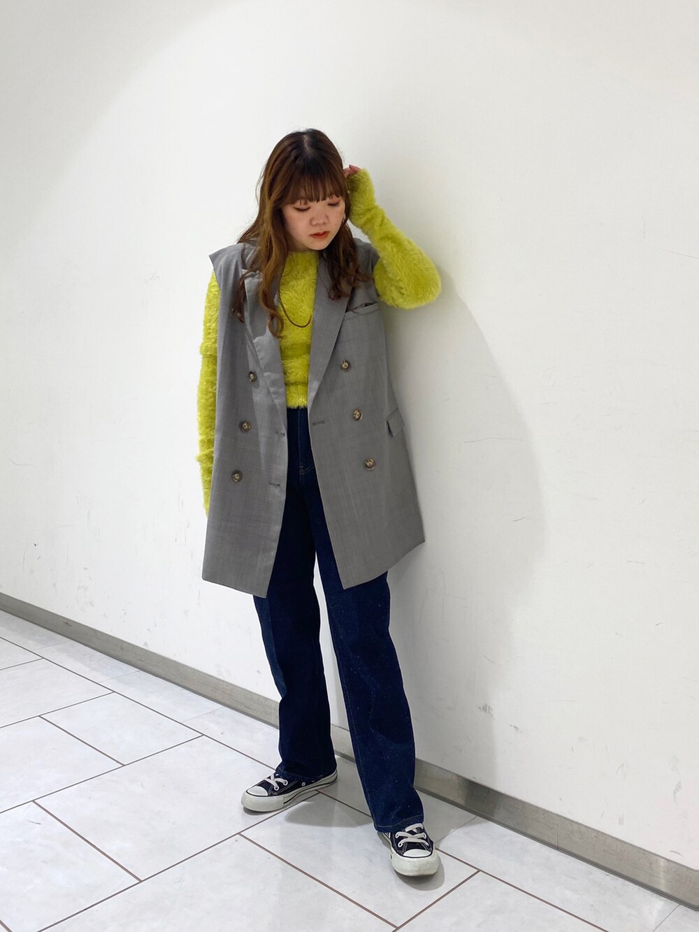 イエロー系のニット/セーター、グレー系のベスト、ブルー系のデニムパンツを着用したレディースの春コーディネートの2枚目の写真