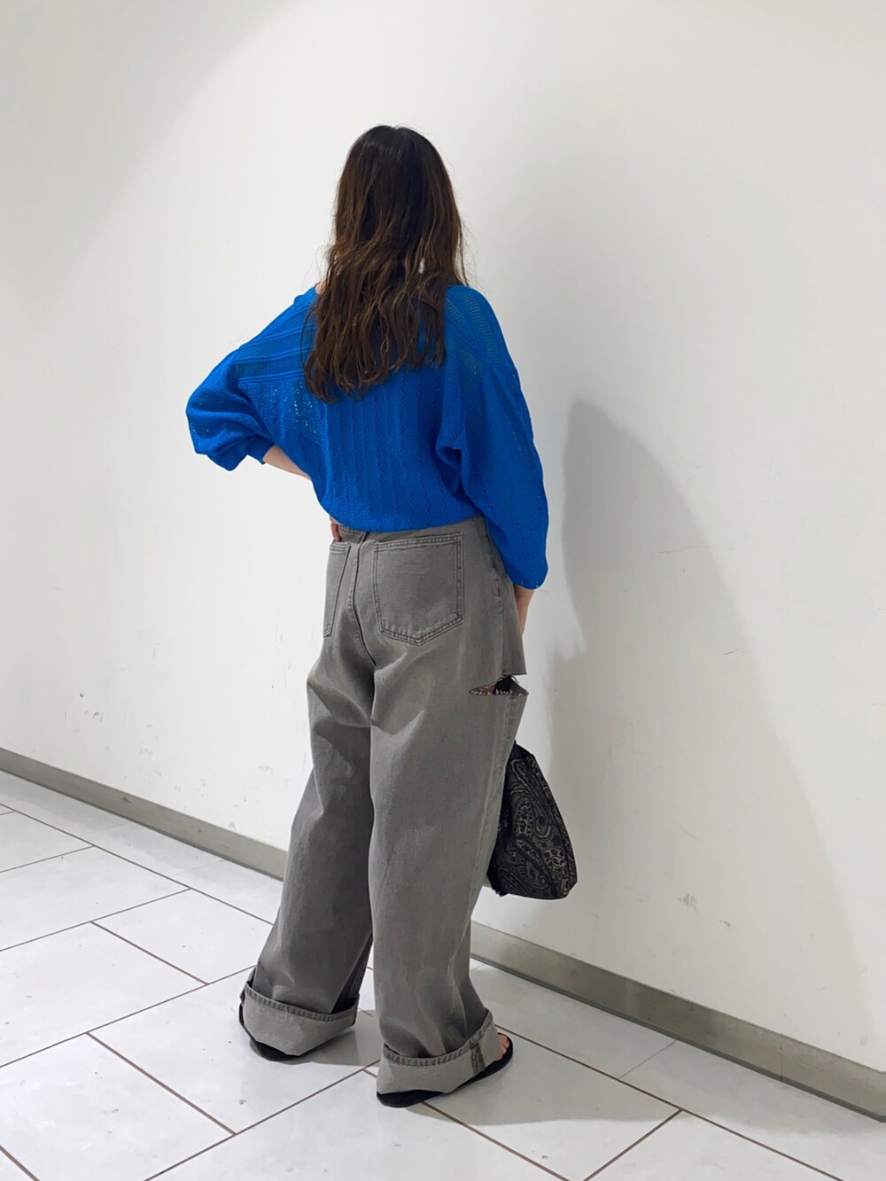 ブルー系のニット/セーター、グレー系のデニムパンツを着用したレディースの春コーディネートの2枚目の写真