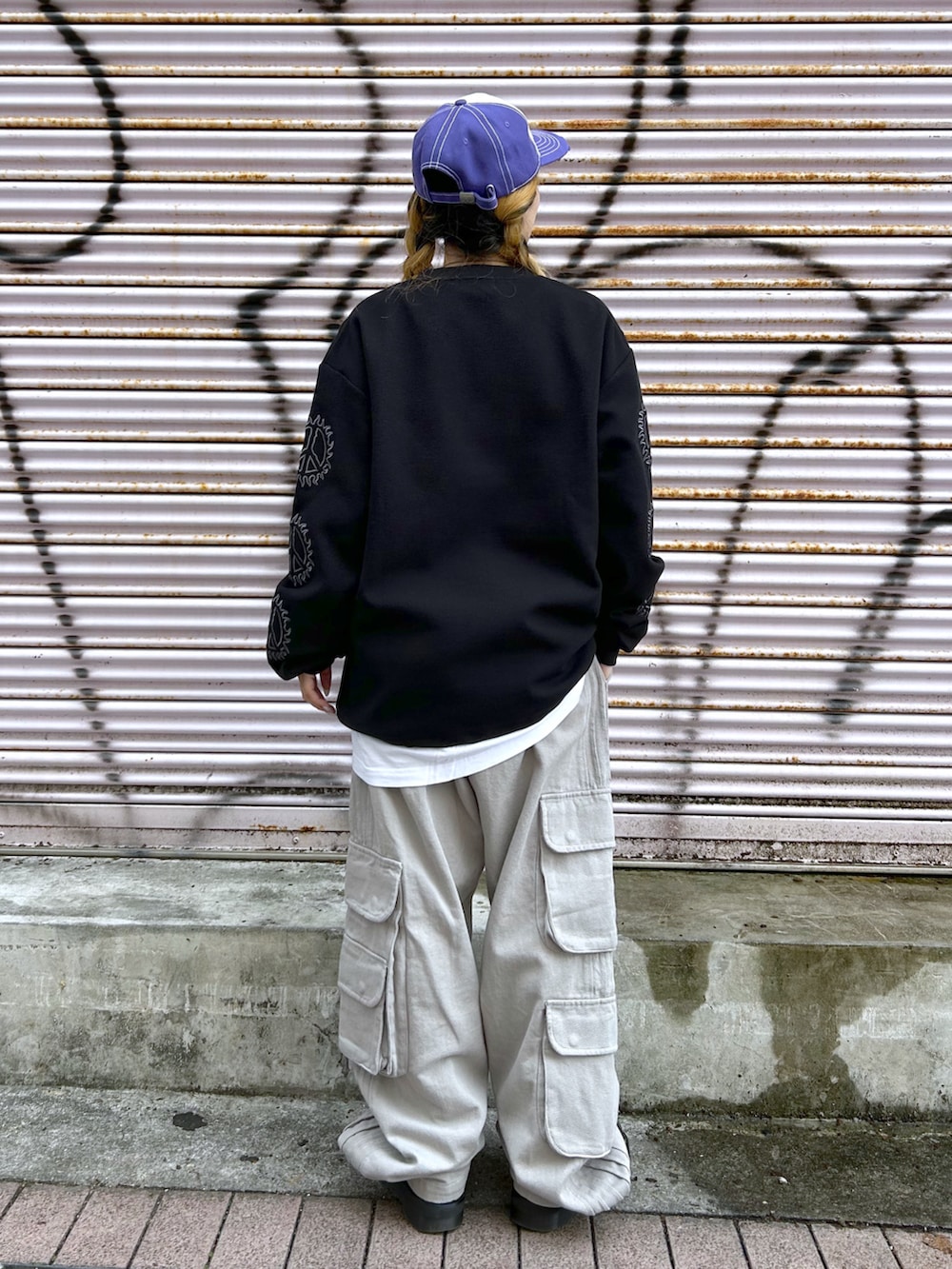 ブラック系のTシャツ/カットソー、グレー系のカーゴパンツ、パープル系のキャップを着用したレディースの春コーディネートの2枚目の写真