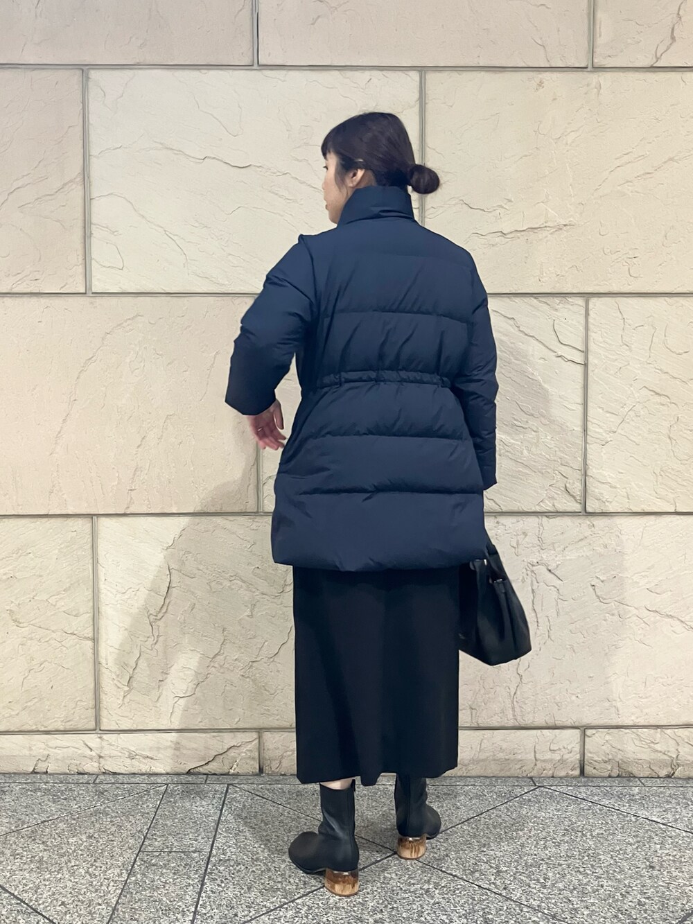 ブルー系のダウンジャケット/コート、イエロー系のニット/セーター、ブラック系のスカートを着用したレディースの冬コーディネートの3枚目の写真