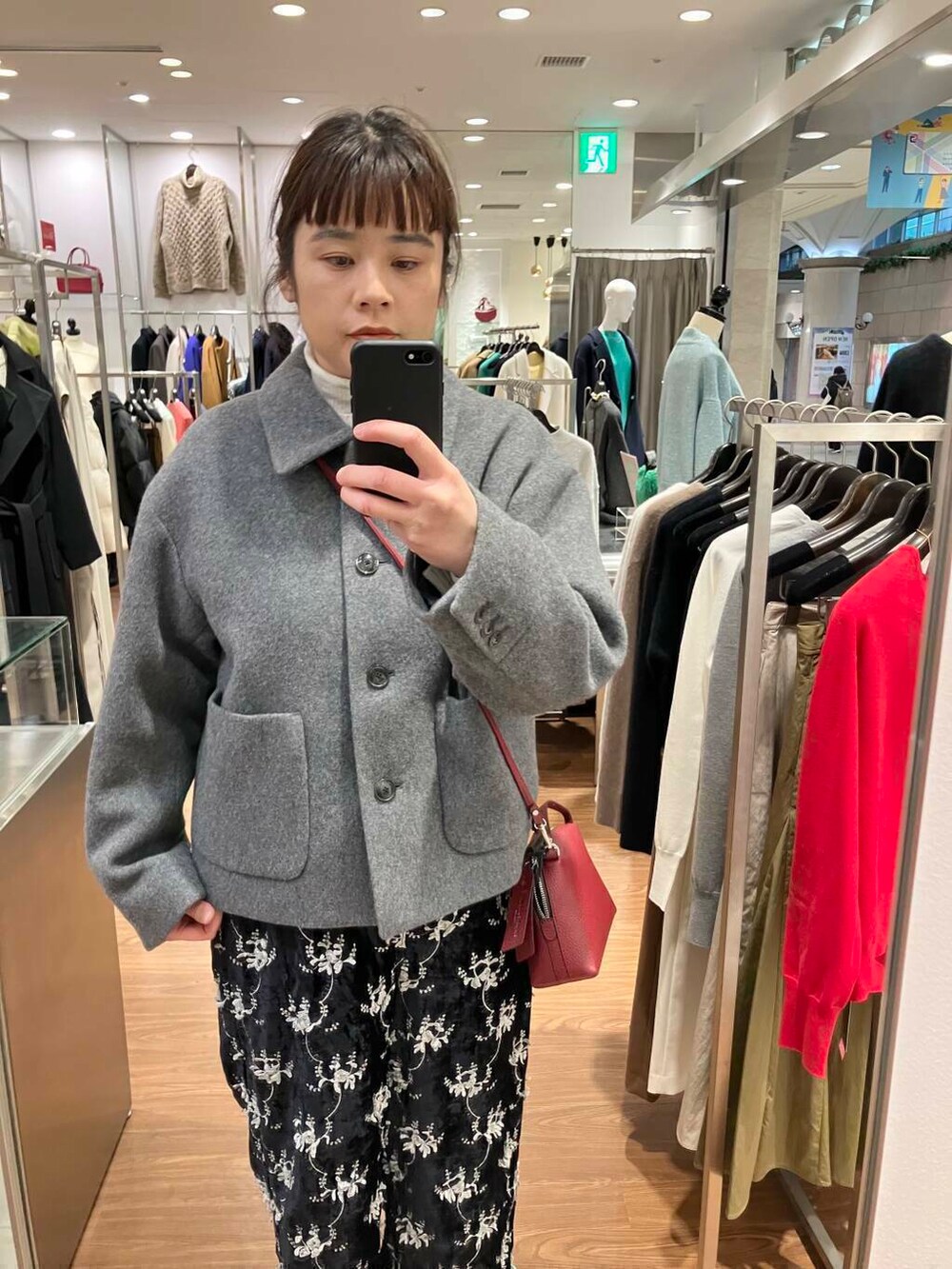 ホワイト系のニット/セーター、グレー系のその他アウター、レッド系のショルダーバッグを着用したレディースの冬コーディネートの2枚目の写真