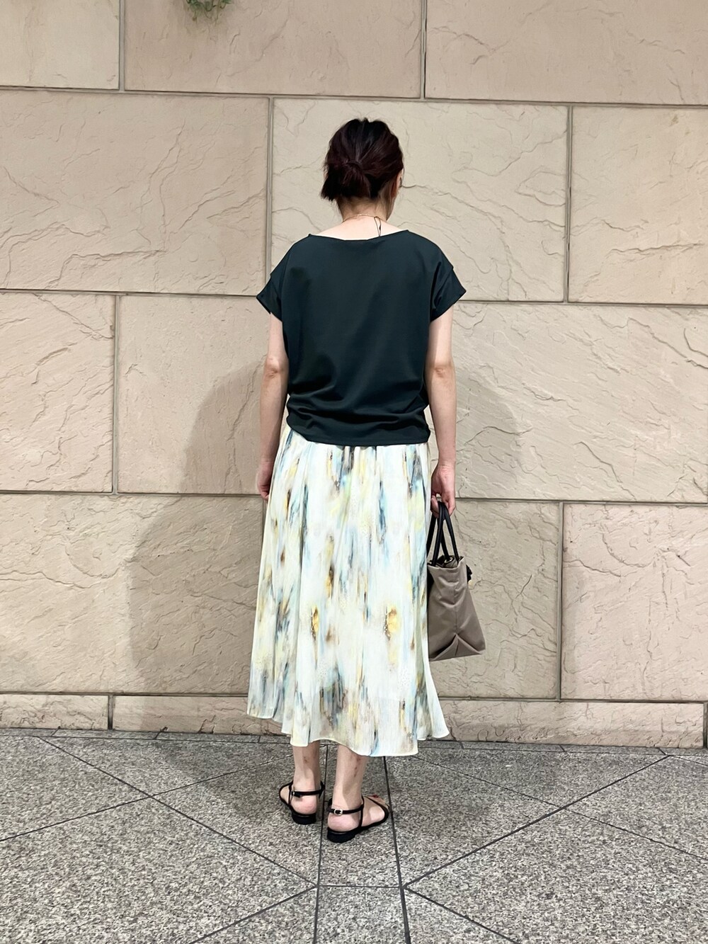 グリーン系のTシャツ/カットソー、ホワイト系のスカート、ベージュ系のトートバッグを着用したレディースの夏コーディネートの3枚目の写真