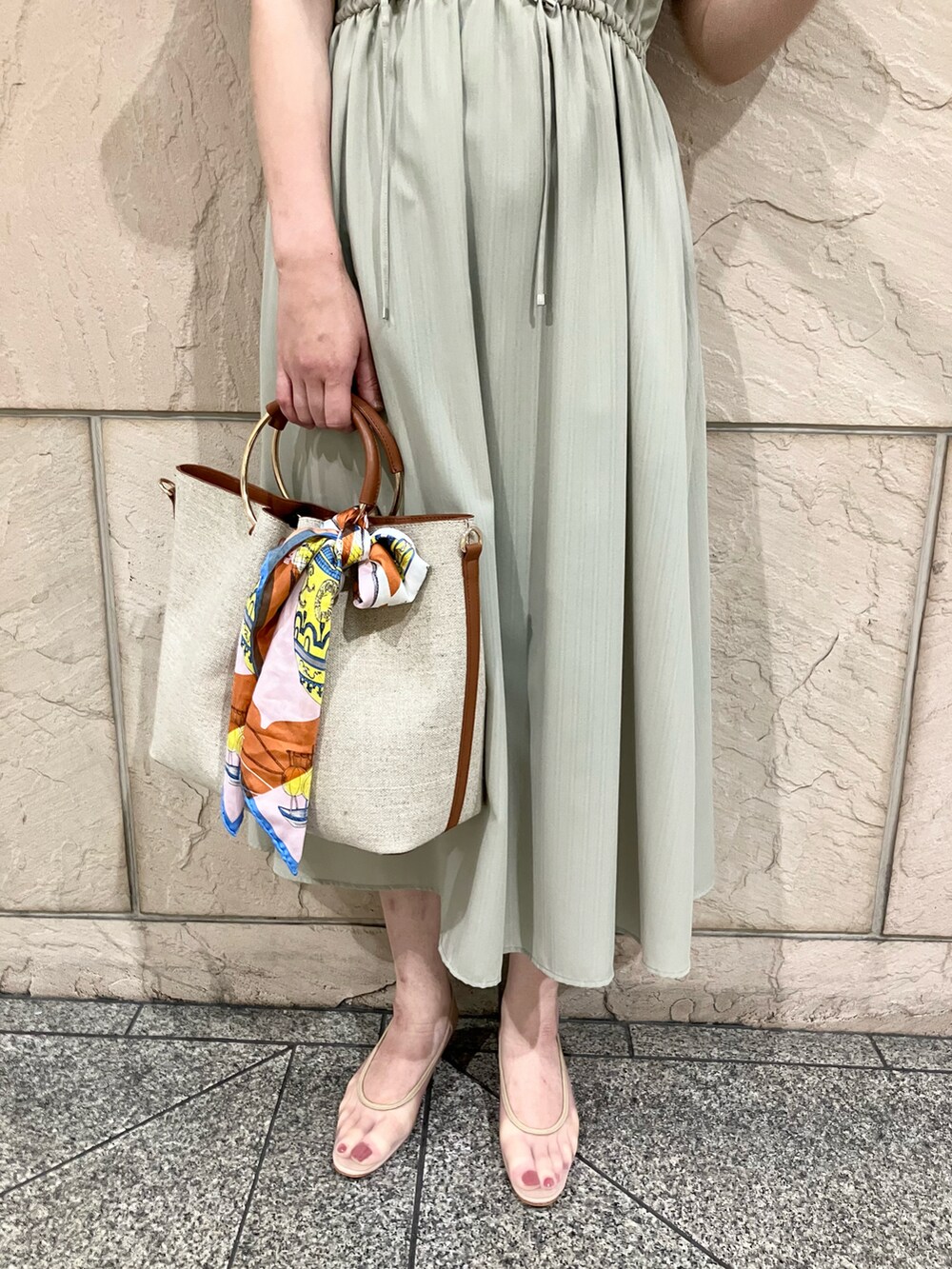 グリーン系のワンピース、ブラウン系のハンドバッグ、ベージュ系のパンプスを着用したレディースの春コーディネートの4枚目の写真