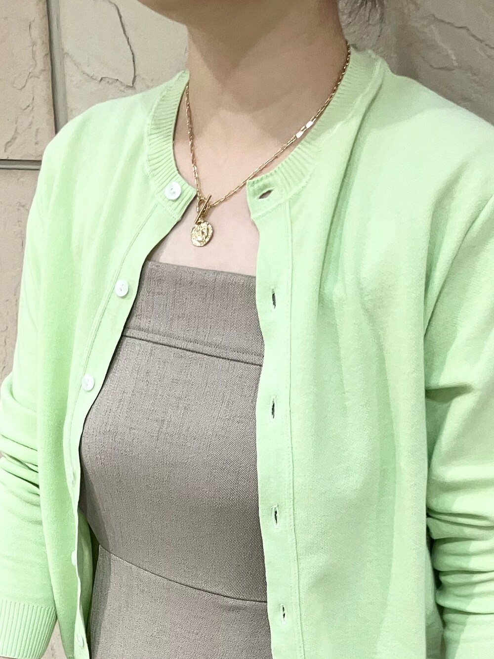 グリーン系のカーディガン/ボレロ、ベージュ系のワンピース/ドレス、ブラック系のかごバッグを着用したレディースの春コーディネートの2枚目の写真