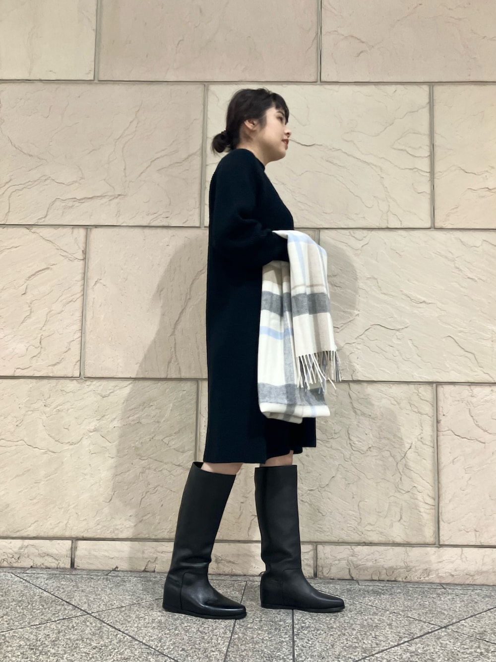 ブラック系のワンピース、ブラック系のブーツ、ホワイト系のストール/ショールを着用したレディースの秋コーディネートの2枚目の写真