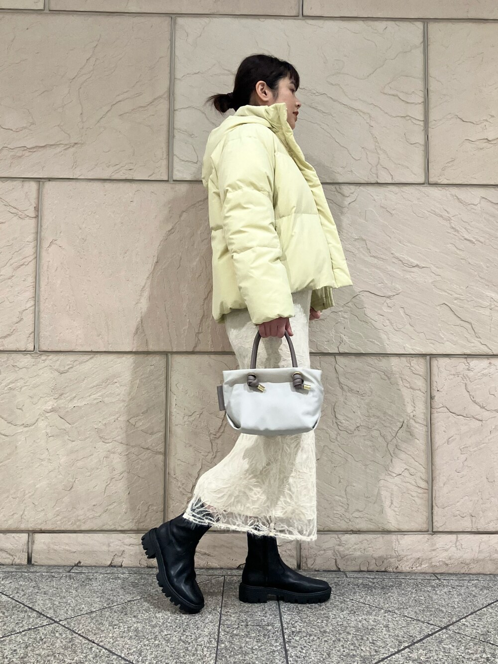 ホワイト系のニット/セーター、ホワイト系のスカート、イエロー系のダウンジャケット/コートを着用したレディースの冬コーディネートの2枚目の写真