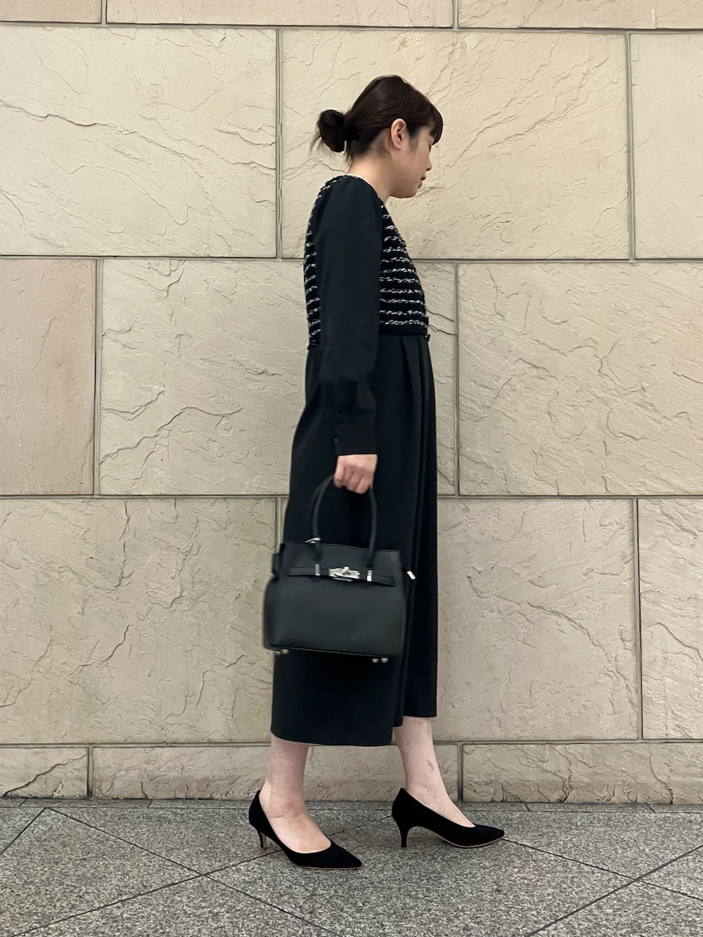 ブラック系のワンピース、ブラック系のパンプス、ブラック系のハンドバッグを着用したレディースの秋コーディネートの2枚目の写真