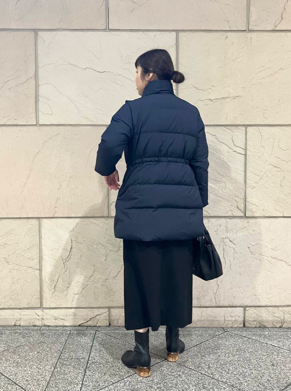 イエロー系のニット/セーター、ブラック系のスカート、ブルー系のダウンジャケット/コートを着用したレディースの冬コーディネートの3枚目の写真