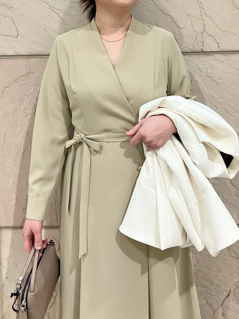 ベージュ系のワンピース、ブラウン系のパンプス、ホワイト系のノーカラージャケットを着用したレディースの冬コーディネートの2枚目の写真