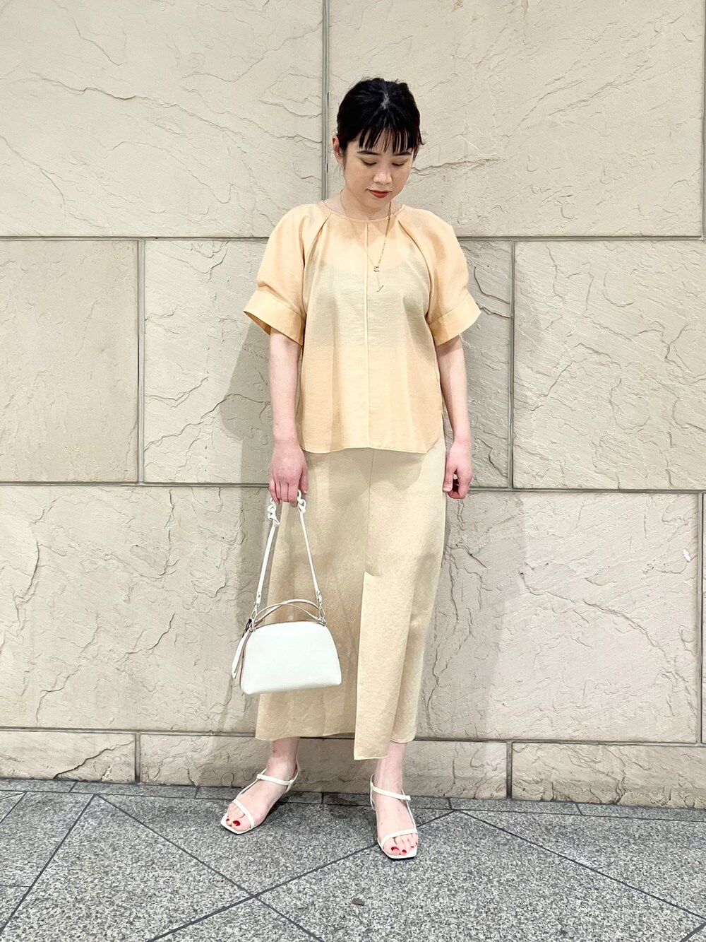 オレンジ系のシャツ/ブラウス、ホワイト系のサンダル、ベージュ系のスカートを着用したレディースの春コーディネートの2枚目の写真