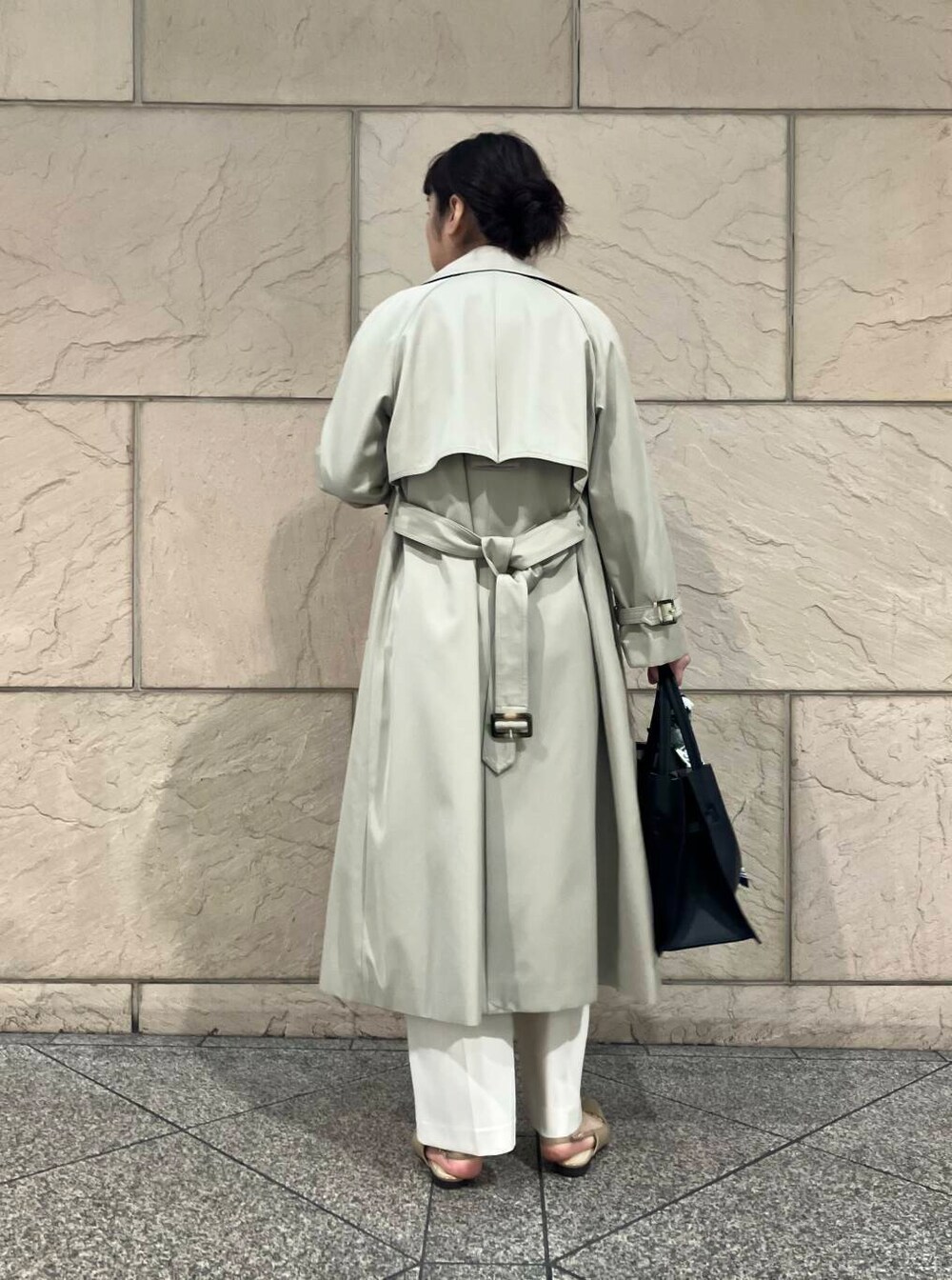 グレー系のトレンチコート、ベージュ系のパンプス、ブラック系のトートバッグを着用したレディースの春コーディネートの3枚目の写真