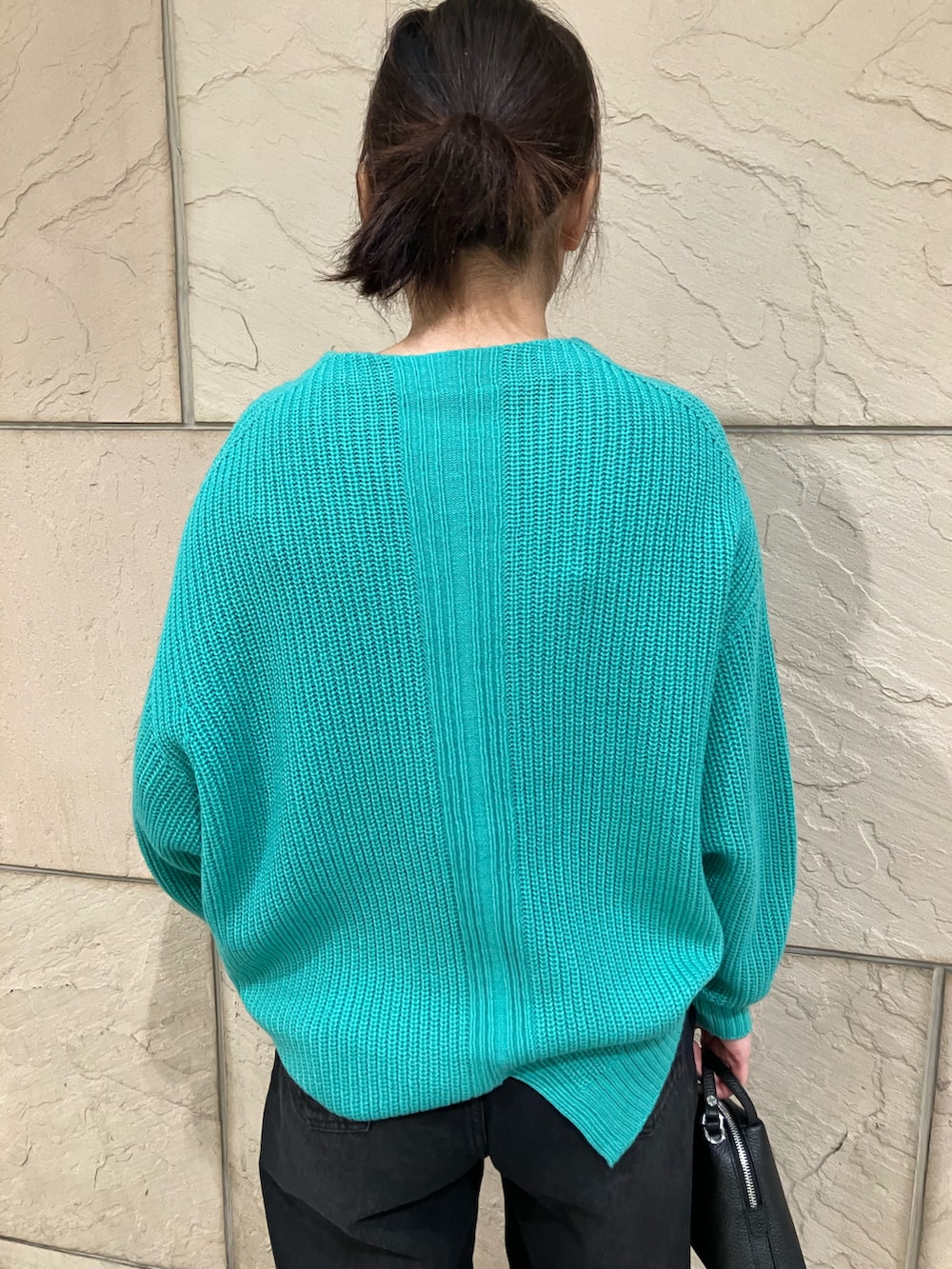 グリーン系のニット/セーター、ブラック系のデニムパンツ、ブラック系のショルダーバッグを着用したレディースの冬コーディネートの3枚目の写真