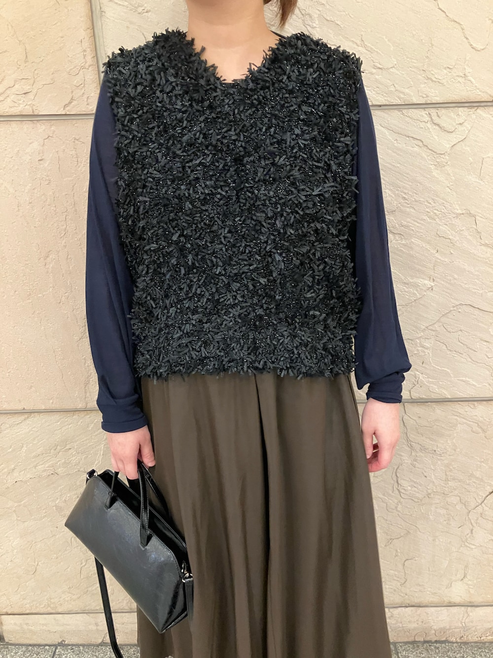 ブルー系のTシャツ/カットソー、ブラック系のベスト、ブラウン系のスカートを着用したレディースの秋コーディネートの4枚目の写真