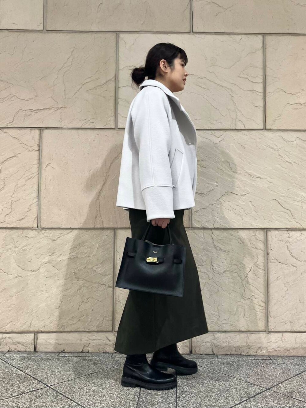 グリーン系のスカート、グレー系のピーコート、ブラック系のブーツを着用したレディースの冬コーディネートの2枚目の写真