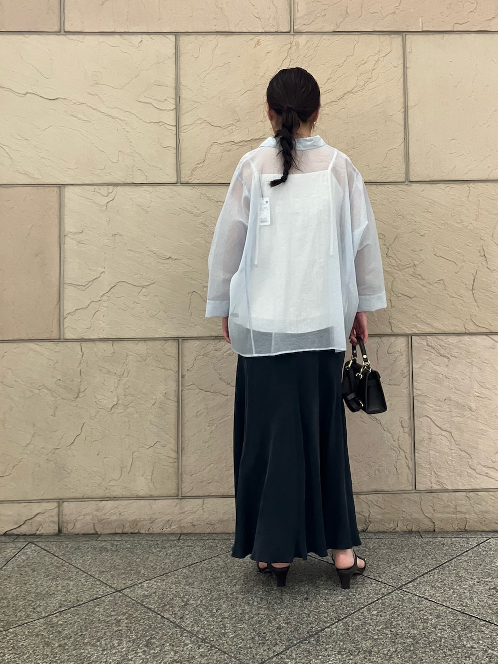 ホワイト系のキャミソール、ブラック系のスカート、ブルー系のトップスを着用したレディースの春コーディネートの3枚目の写真
