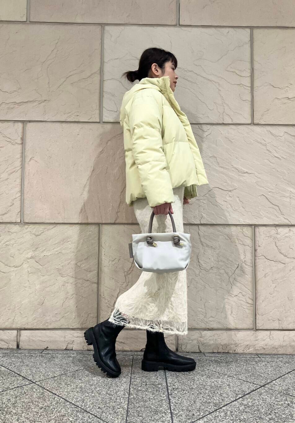 ブラック系のブーツ、イエロー系のダウンジャケット/コート、ホワイト系のスカートを着用したレディースの冬コーディネートの2枚目の写真