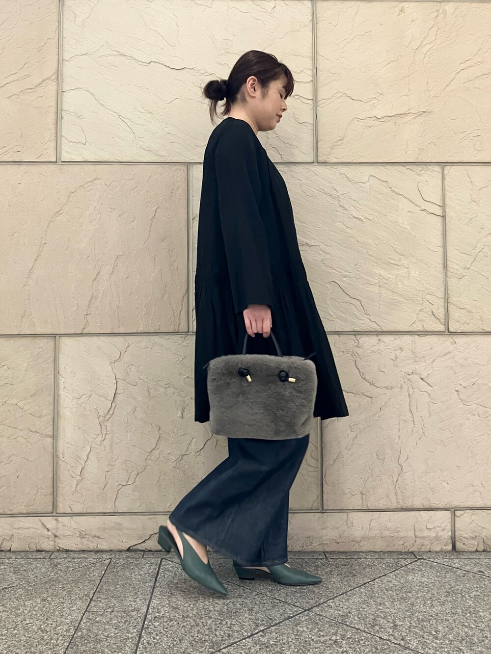 ブラック系のワンピース、ブラウン系のハンドバッグ、ブルー系のデニムパンツを着用したレディースの秋コーディネートの2枚目の写真