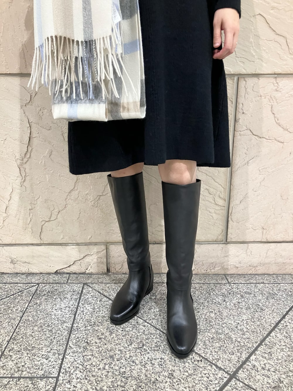 ブラック系のワンピース、ブラック系のブーツ、ホワイト系のストール/ショールを着用したレディースの秋コーディネートの4枚目の写真