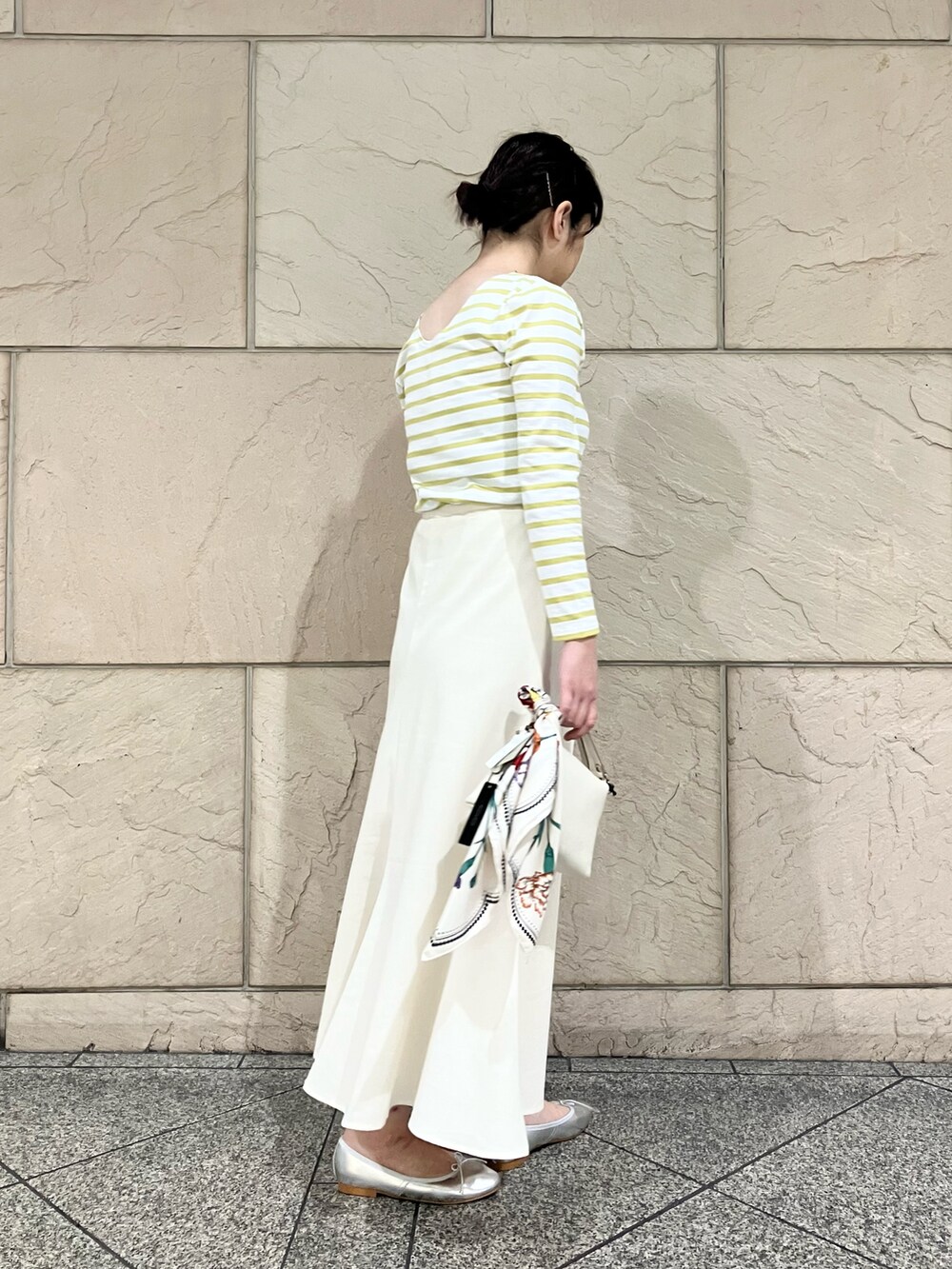 イエロー系のTシャツ/カットソー、ホワイト系のスカート、シルバー系のバレエシューズを着用したレディースの春コーディネートの5枚目の写真