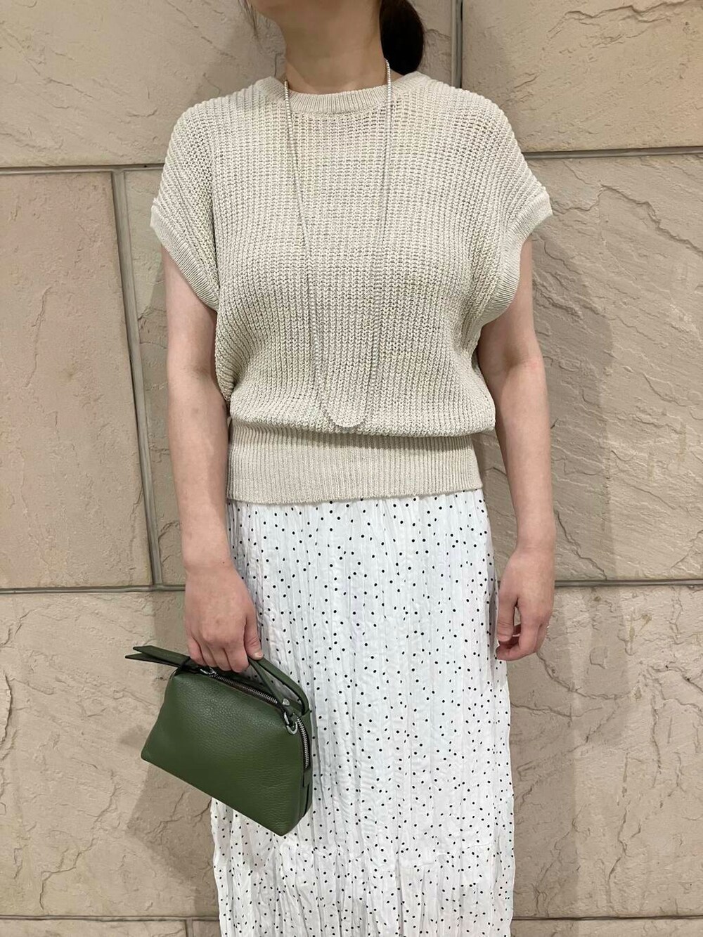 ベージュ系のベスト、ホワイト系のスカート、シルバー系のネックレスを着用したレディースの夏コーディネートの4枚目の写真