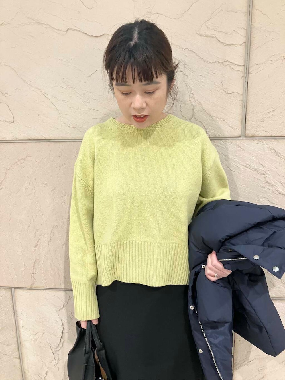 イエロー系のニット/セーター、ブラック系のスカート、ブルー系のダウンジャケット/コートを着用したレディースの冬コーディネートの7枚目の写真