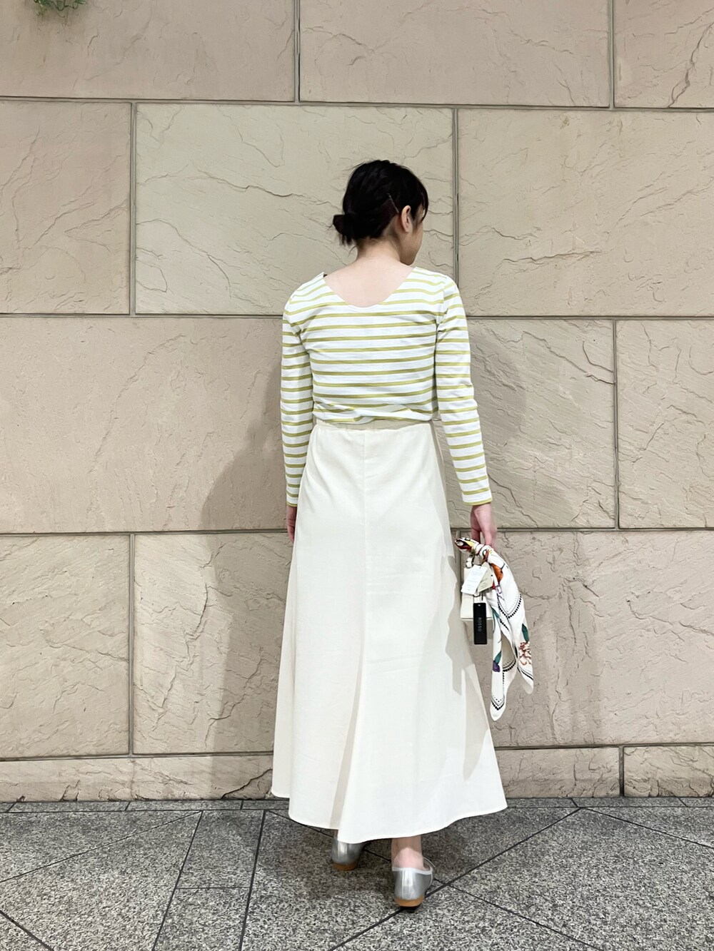 イエロー系のTシャツ/カットソー、ホワイト系のスカート、シルバー系のバレエシューズを着用したレディースの春コーディネートの2枚目の写真