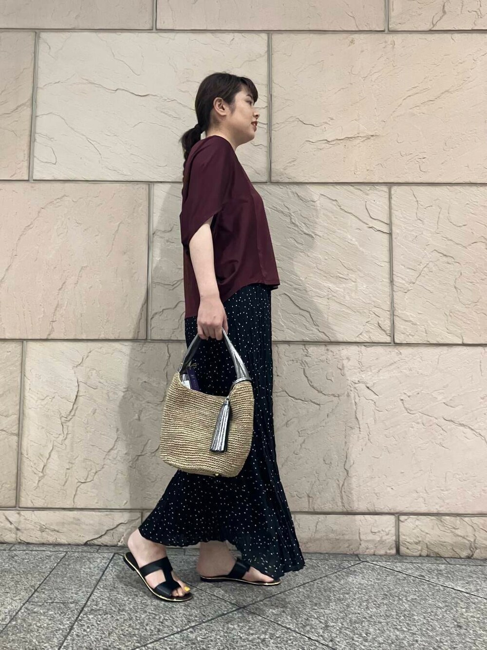 ブラウン系のかごバッグ、レッド系のTシャツ/カットソー、ブラック系のスカートを着用したレディースの夏コーディネートの2枚目の写真