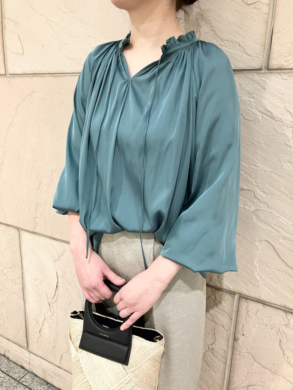 グリーン系のシャツ/ブラウス、ベージュ系のパンツ、ベージュ系のハンドバッグを着用したレディースの春コーディネートの3枚目の写真