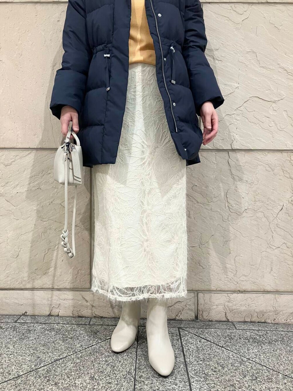 ベージュ系のブーツ、ブルー系のダウンジャケット/コート、オレンジ系のニット/セーターを着用したレディースの冬コーディネートの5枚目の写真