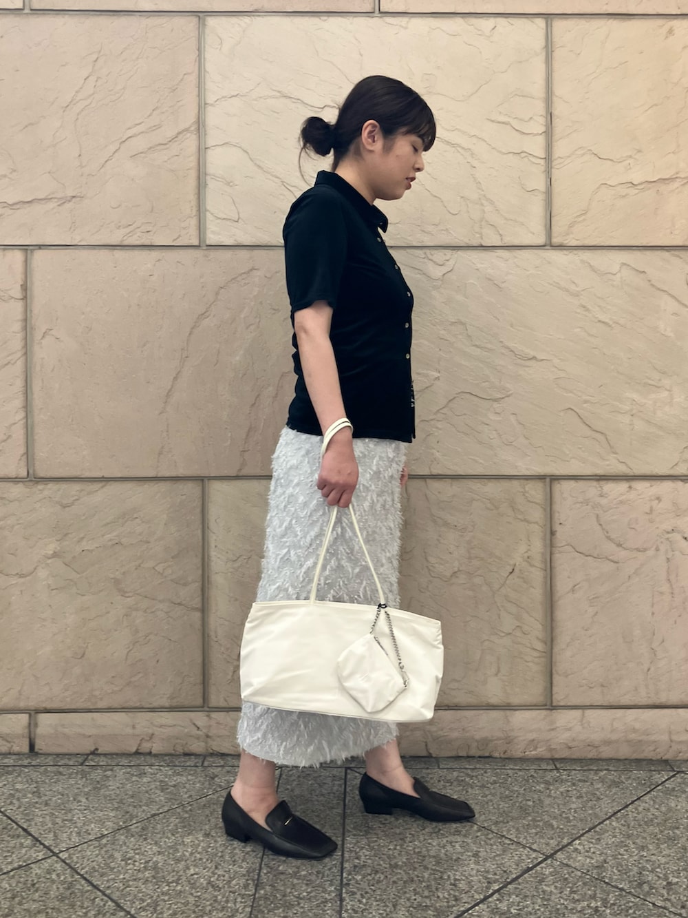 グレー系のスカート、ブラック系のTシャツ/カットソー、ホワイト系のトートバッグを着用したレディースの夏コーディネートの2枚目の写真