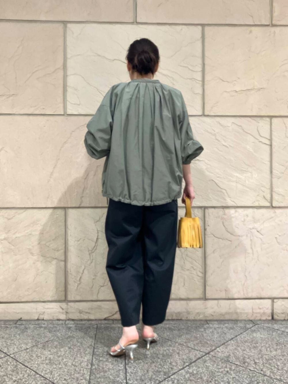 グリーン系のブルゾン、グレー系のその他パンツ、イエロー系のハンドバッグを着用したレディースの春コーディネートの3枚目の写真