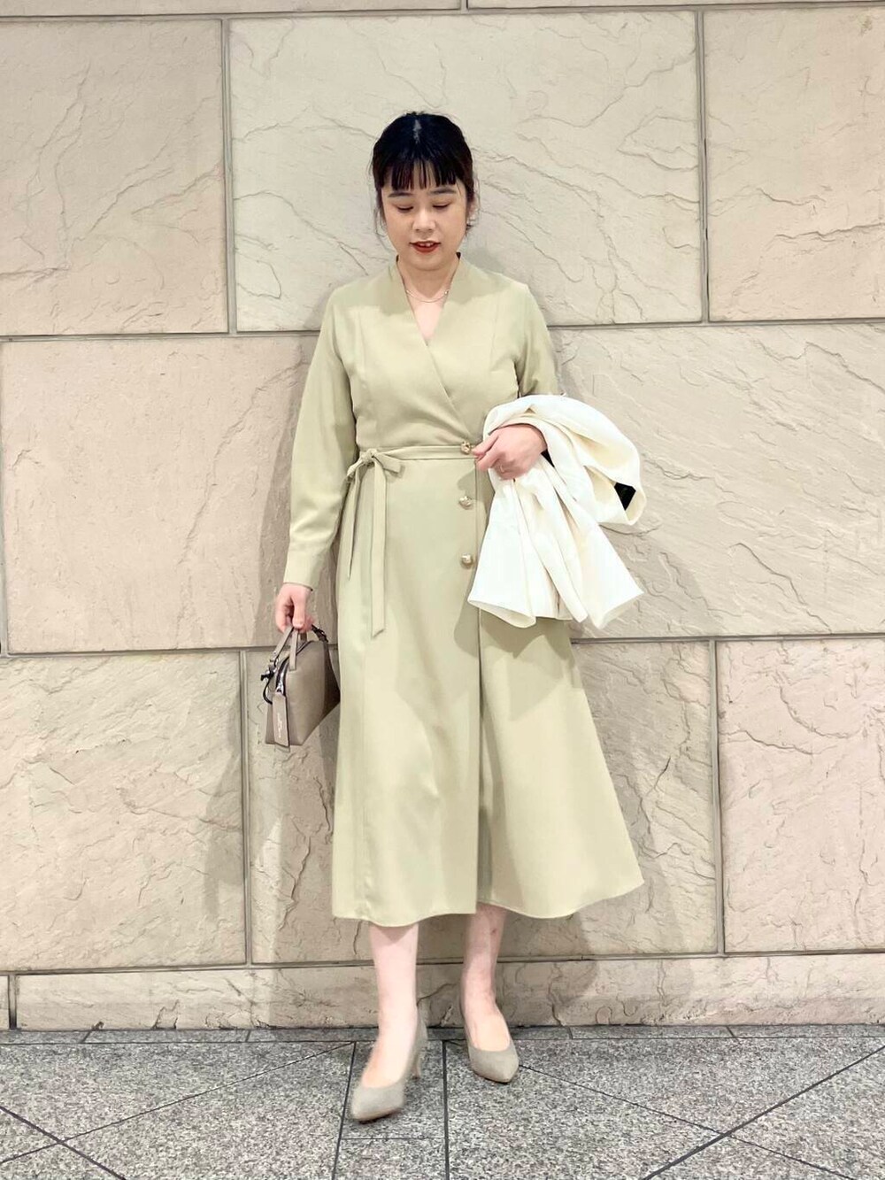 ブラウン系のパンプス、ホワイト系のノーカラージャケット、ベージュ系のワンピースを着用したレディースの冬コーディネートの2枚目の写真