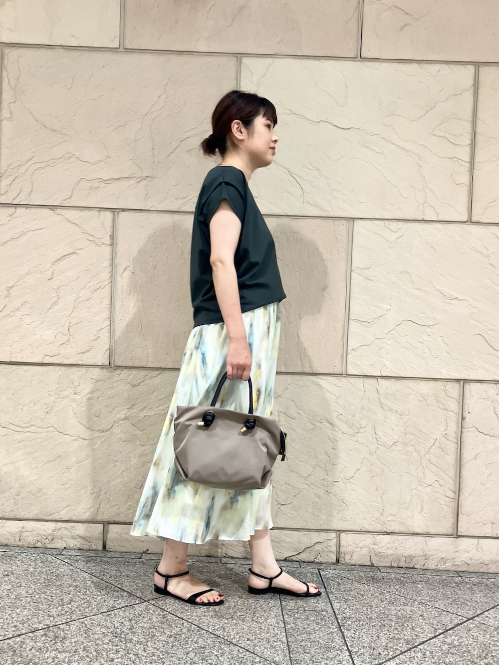 グリーン系のTシャツ/カットソー、ホワイト系のスカート、ベージュ系のトートバッグを着用したレディースの夏コーディネートの2枚目の写真
