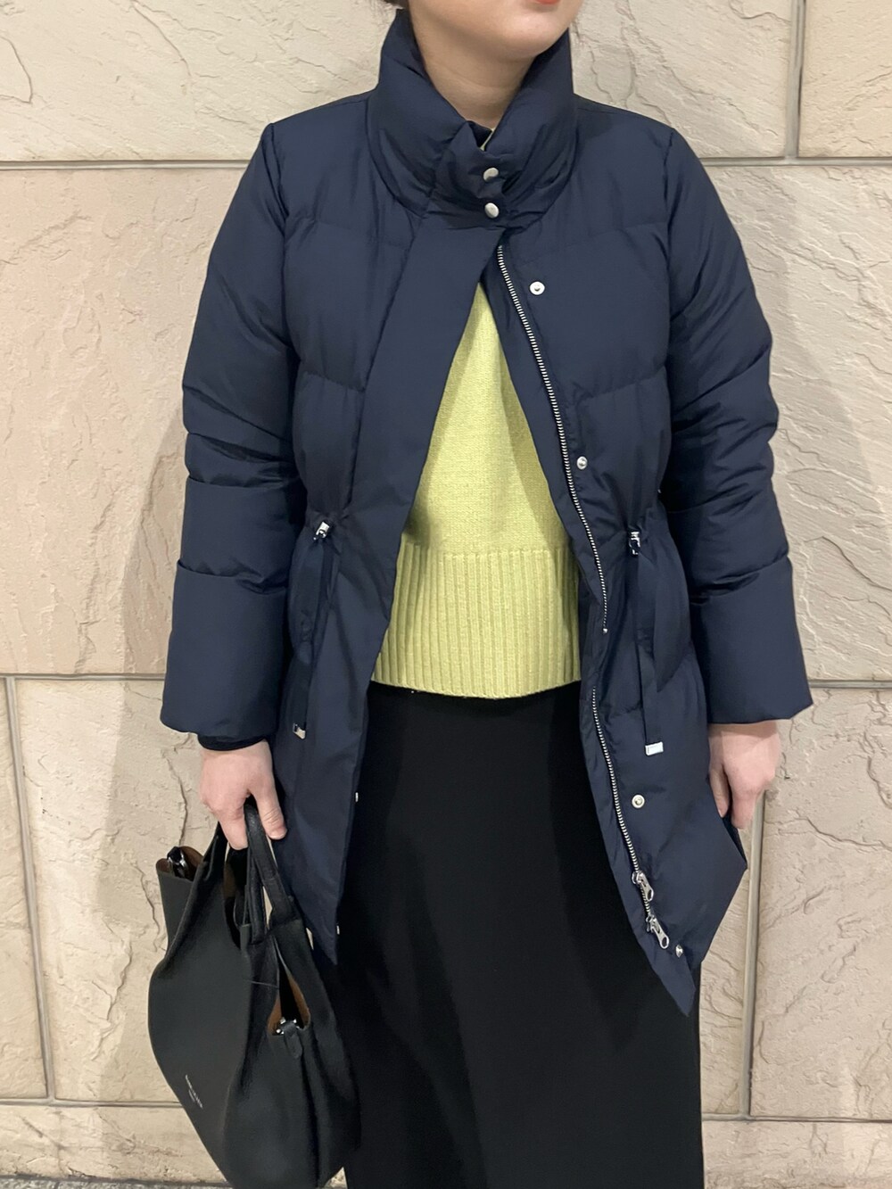 ブルー系のダウンジャケット/コート、イエロー系のニット/セーター、ブラック系のスカートを着用したレディースの冬コーディネートの4枚目の写真