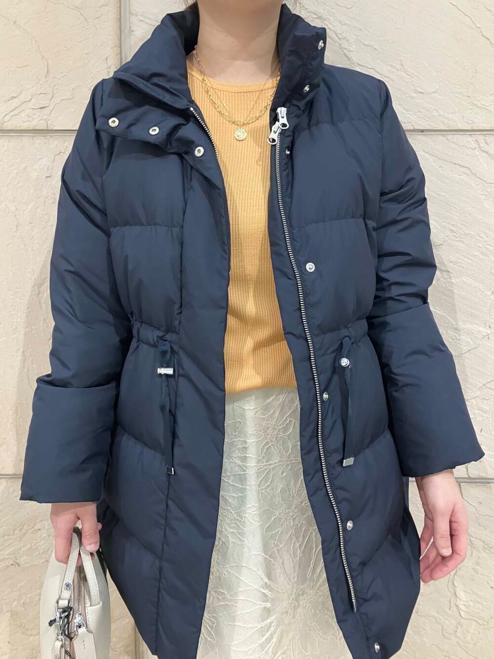 ベージュ系のブーツ、ブルー系のダウンジャケット/コート、オレンジ系のニット/セーターを着用したレディースの冬コーディネートの4枚目の写真