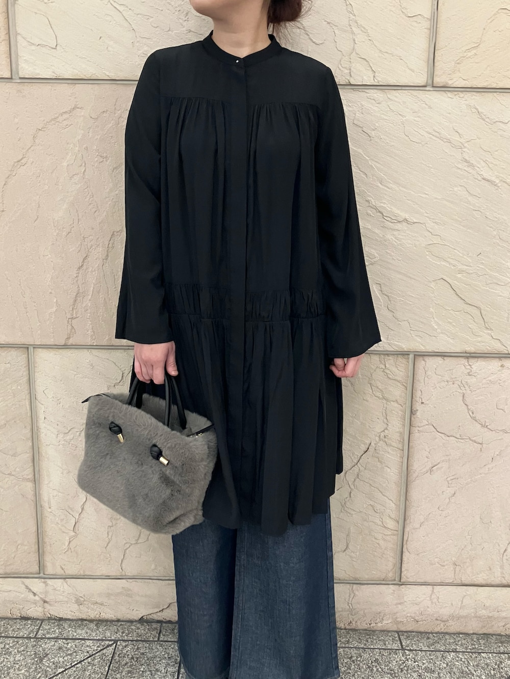 ブラック系のワンピース、ブラウン系のハンドバッグ、ブルー系のデニムパンツを着用したレディースの秋コーディネートの4枚目の写真