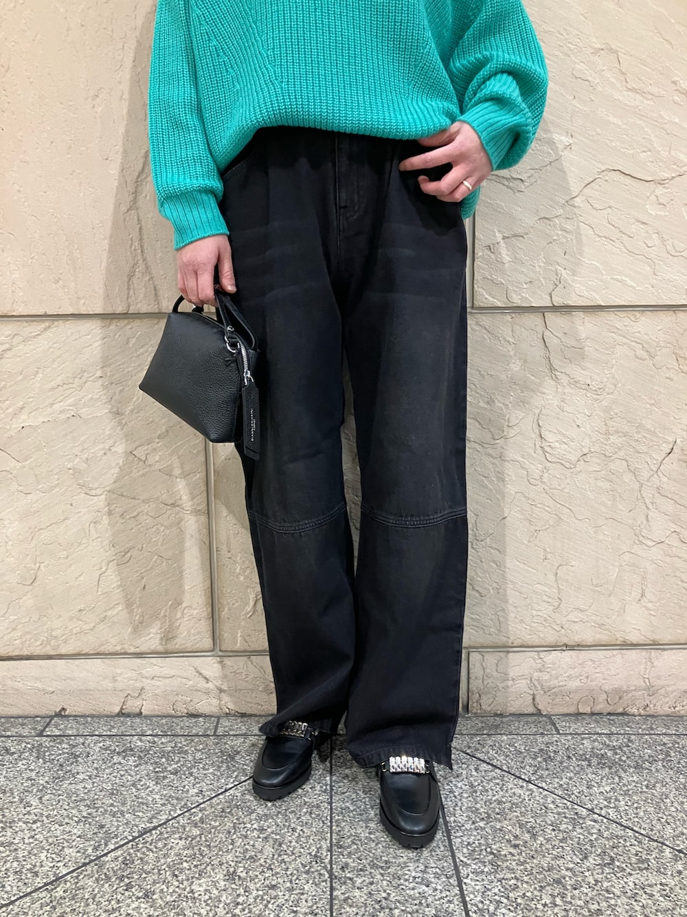 グリーン系のニット/セーター、ブラック系のデニムパンツ、ブラック系のショルダーバッグを着用したレディースの冬コーディネートの5枚目の写真