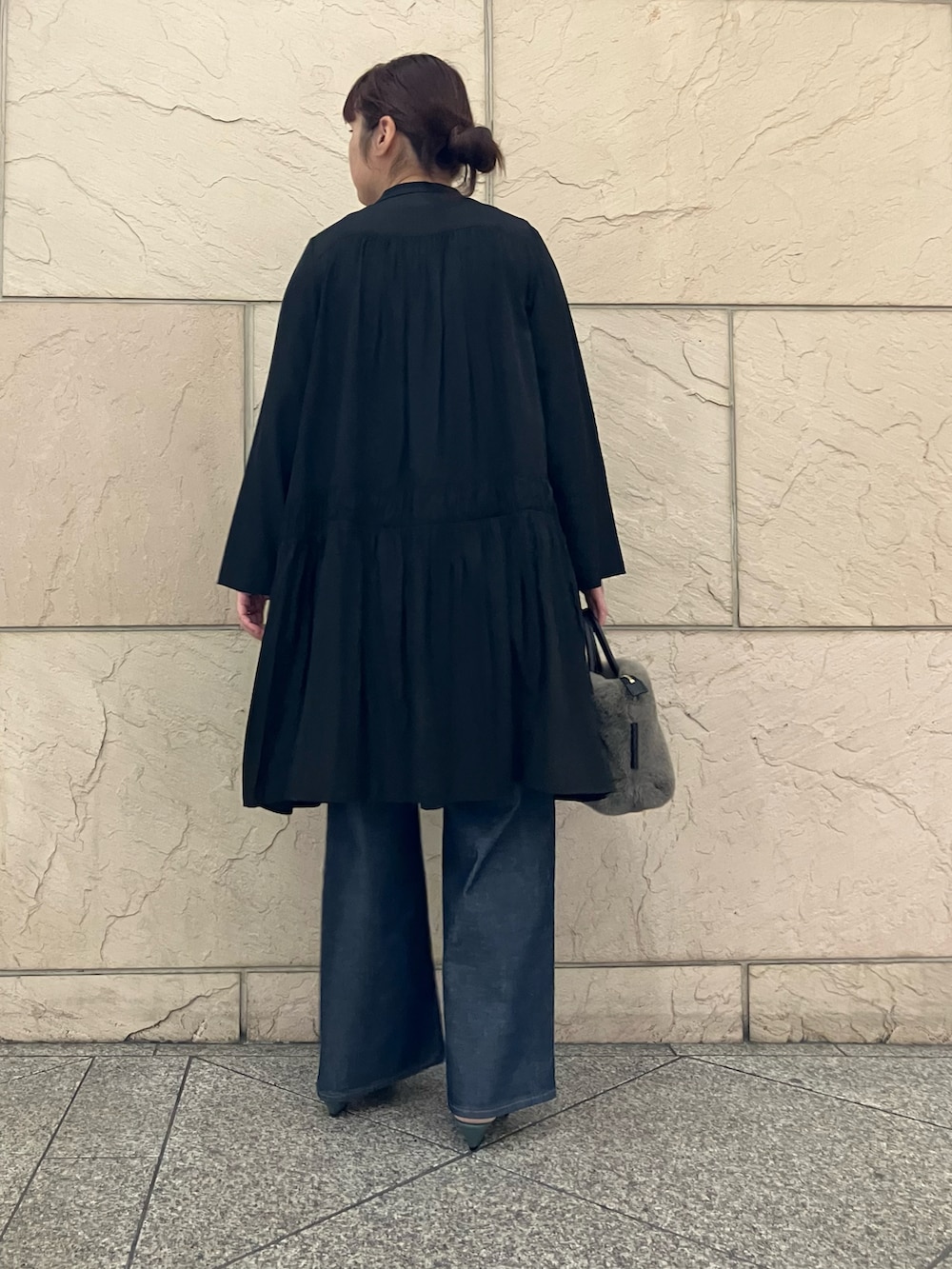 ブラック系のワンピース、ブラウン系のハンドバッグ、ブルー系のデニムパンツを着用したレディースの秋コーディネートの3枚目の写真