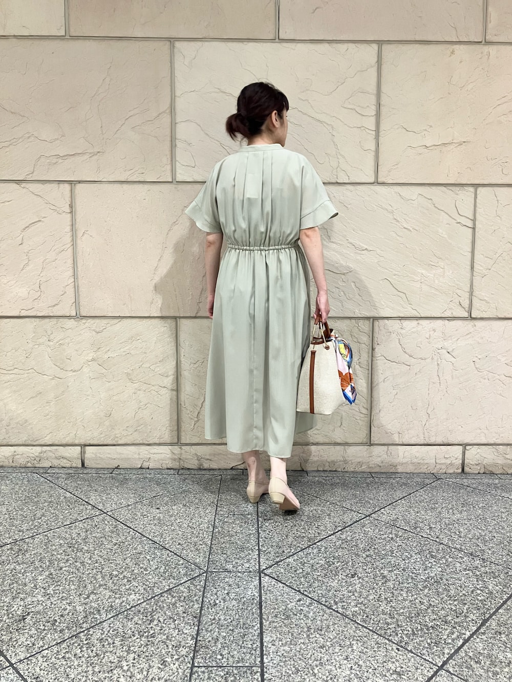 グリーン系のワンピース、ブラウン系のハンドバッグ、ベージュ系のパンプスを着用したレディースの春コーディネートの2枚目の写真