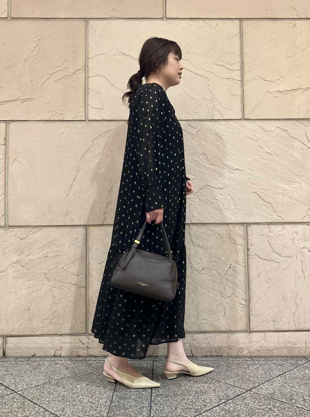ブラック系のワンピース、ベージュ系のパンプス、ブラウン系のバッグを着用したレディースの夏コーディネートの2枚目の写真