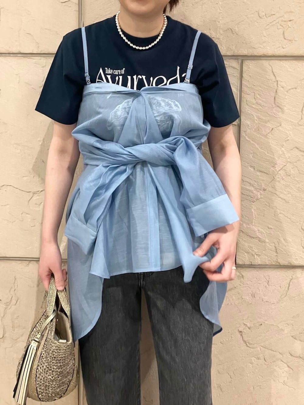 ゴールド系のかごバッグ、ブルー系のシャツ/ブラウス、ブルー系のTシャツ/カットソーを着用したレディースの春コーディネートの3枚目の写真