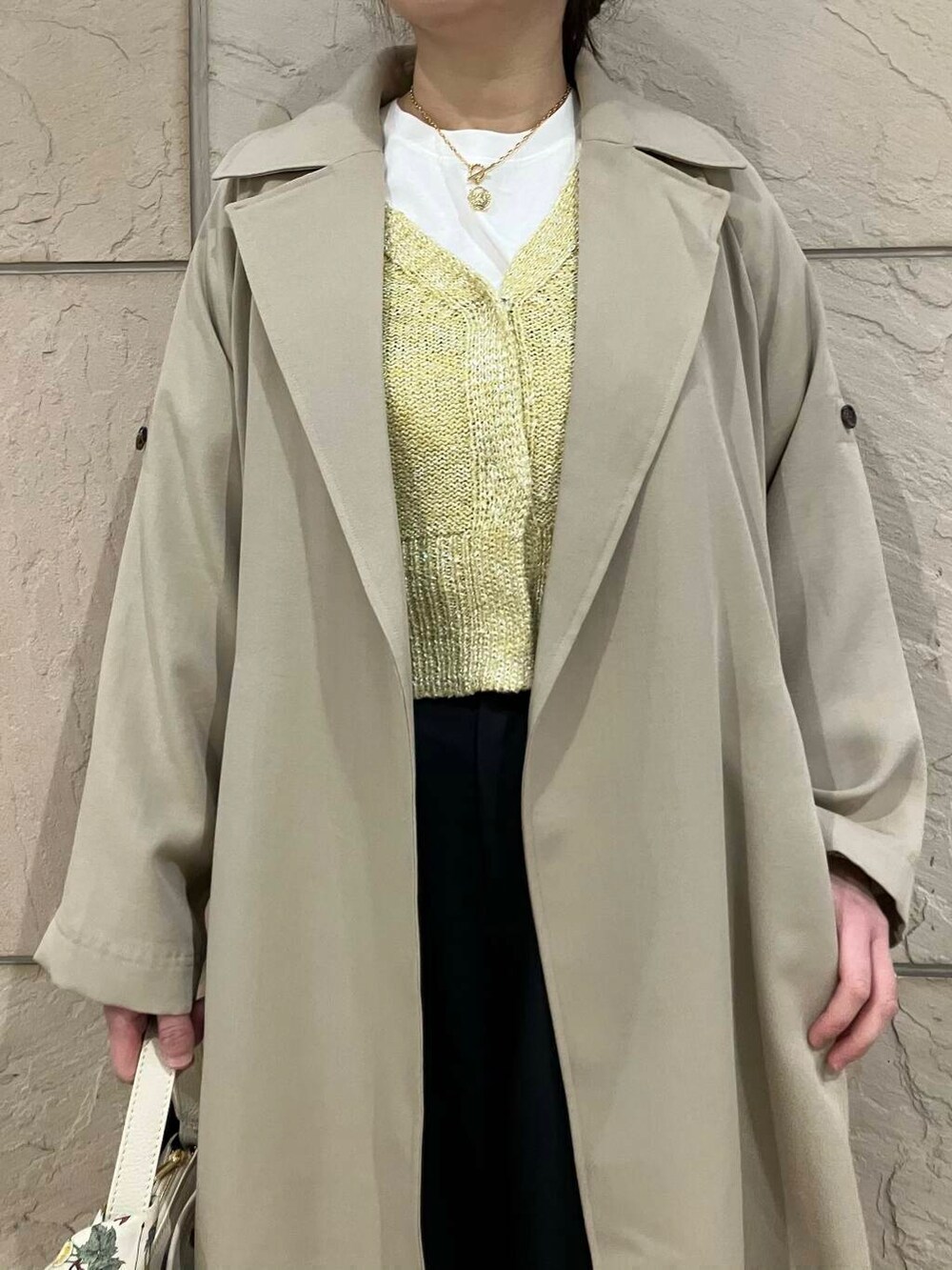 ベージュ系のトレンチコート、イエロー系のカーディガン/ボレロ、グレー系のその他パンツを着用したレディースの冬コーディネートの4枚目の写真